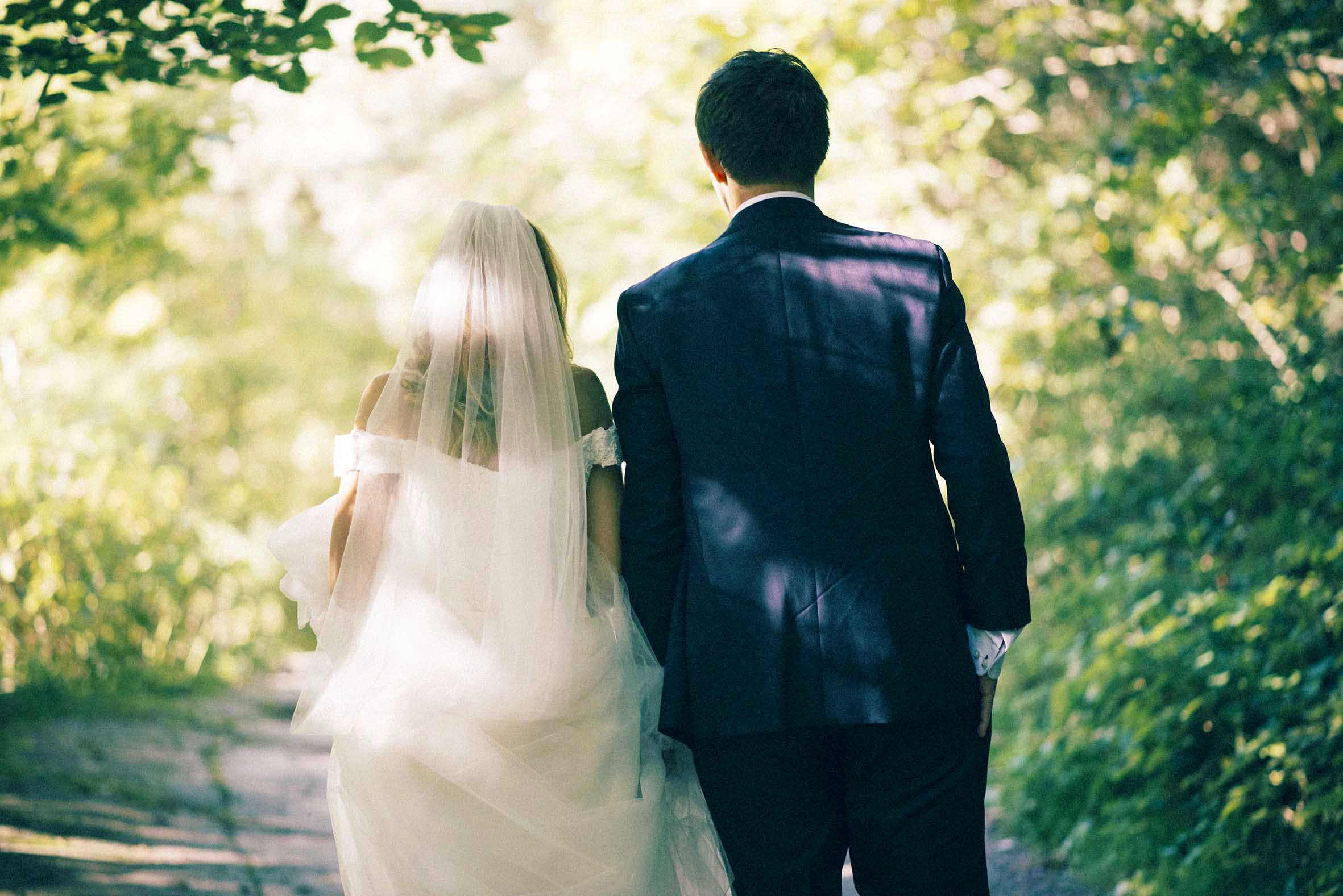 Høstbryllup fra Oslo.Brud og brudgom går hånd i hånd i skogen.