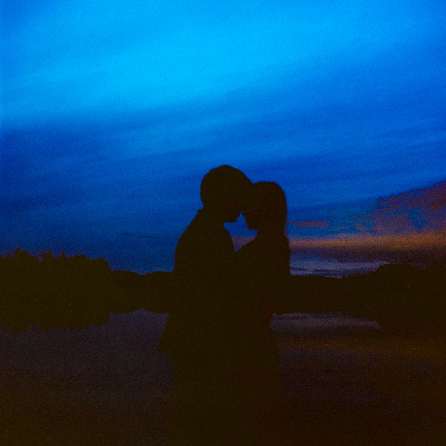 par omfavner hverandre i den blå timen, fanget av bryllupsfotograf Oslo